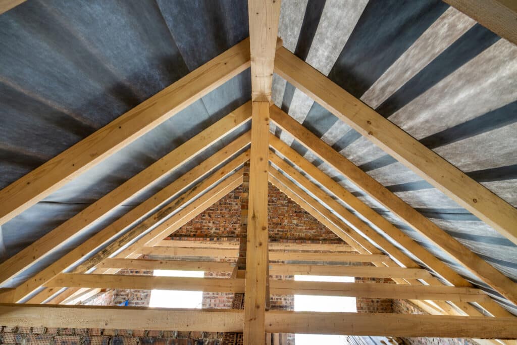 Charpente en bois : construction d'une toiture de maison Charpente en bois d'une toiture sur murs de briques en cours de construction avec membrane isolante.