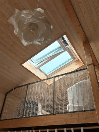 Mezzanine en Bois avec Puits de Lumière et Filet Design Mezzanine en bois avec puits de lumière, suspension florale blanche et filet de protection.